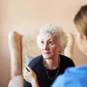 Older adult seated in a cozy living room smiling during a video call on a tablet with family members.